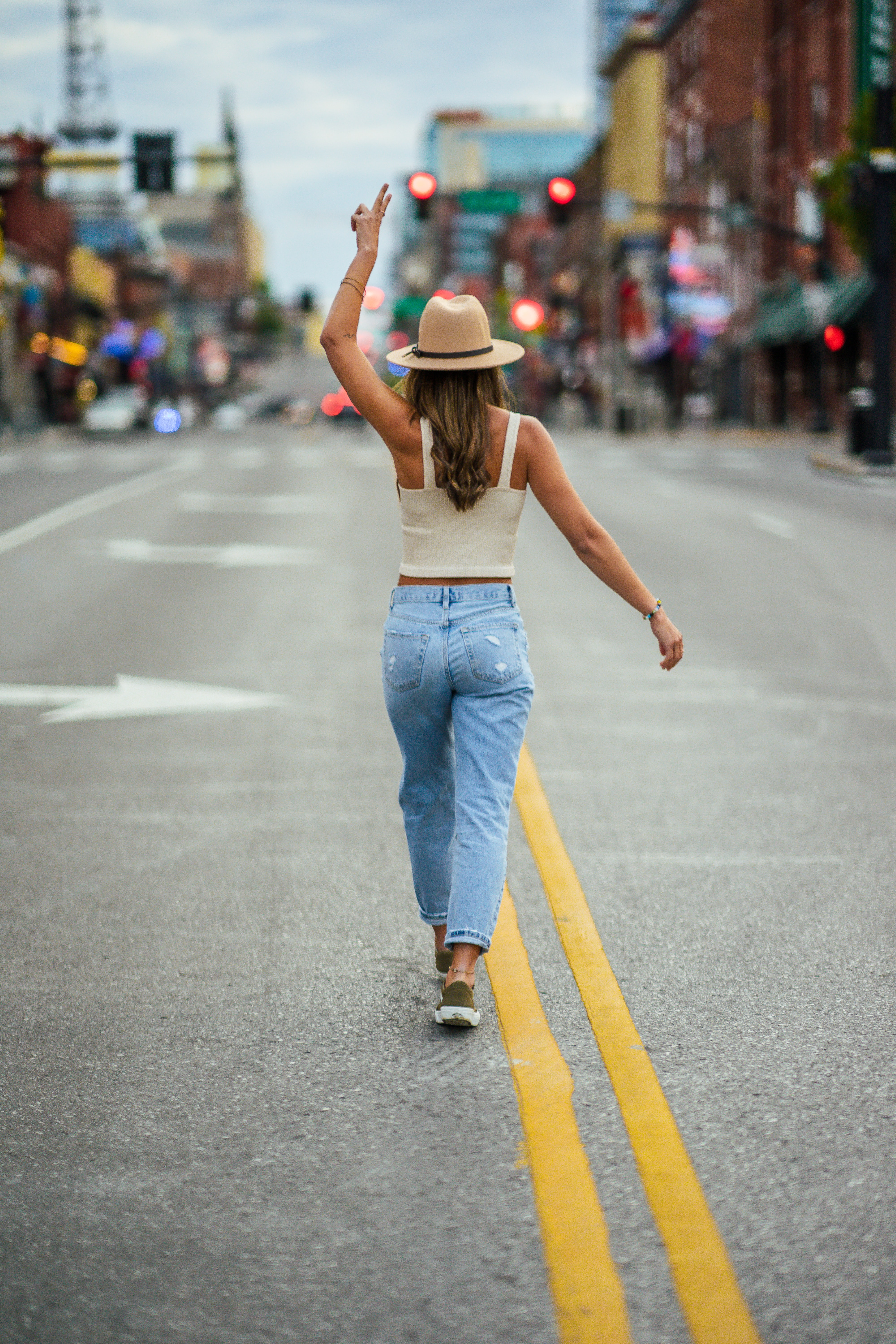 Visit Downtown Nashville Woman standing in the middle of Broadway with a cowboy hat on